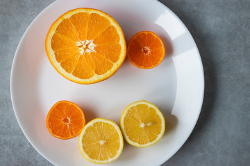 Slices of orange, lemon and mandarin on a white plate. Citrus fruit.