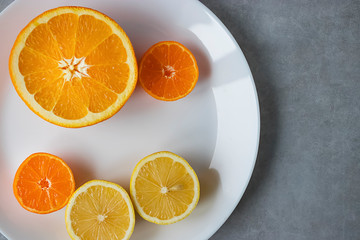 Slices of orange, lemon and mandarin on a white plate. Citrus fruit.