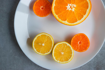 Slices of orange, lemon and mandarin on a white plate. Citrus fruit.