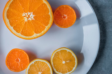Slices of orange, lemon and mandarin on a white plate. Citrus fruit.