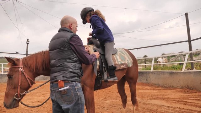 Coach helps girl to ride the horse