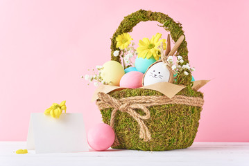 Easter concept. Easter eggs in decorative basket with flowers on a pink background
