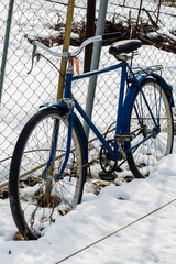 old Bicycle leaning against the fence in winter