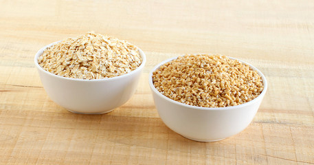 Healthy food oats and steel-cut oats each in a bowl on a wooden background.