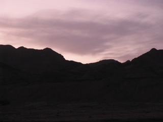 Desierto de Dahab, montañas de Egipto en la noche fotos contra del sol y nubes moradas violetas