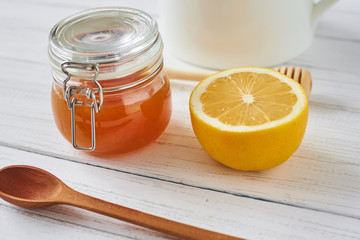 Honey in glass jar and lemon on white background close up