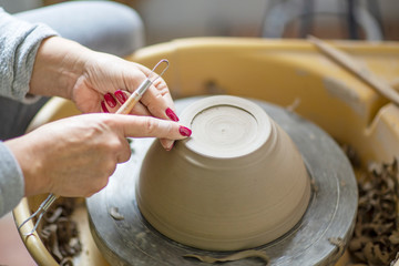 Womans hands making pot from clay on pottery wheel