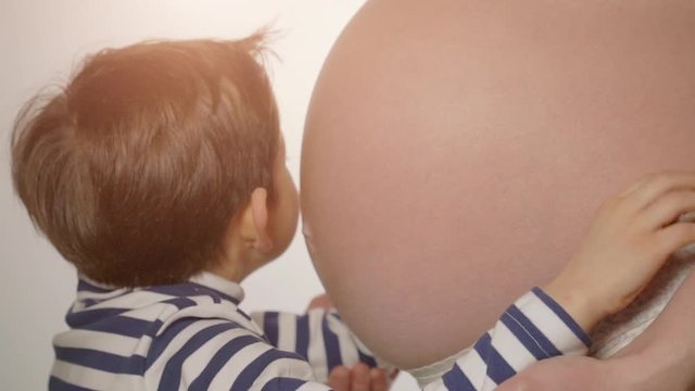 Little boy hugging mother's pregnant belly