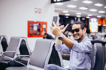 Asian man with backpack  traveler using the smart mobile phone for Video call and taking at an airport