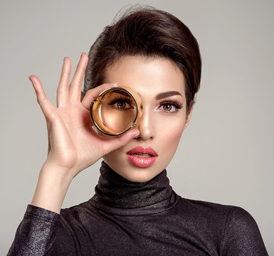 Beautiful young woman looks through bracelet. Eyesight. Vision. Gaze.