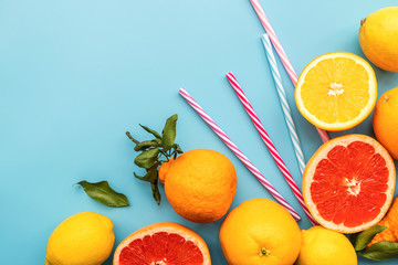 fresh citrus fruit with drinking straws on blue background top view flat lay with copy space