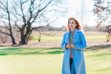 Nice girl in blue wool coat and sweater in casual spring style in park. Outfit fashion concept 
