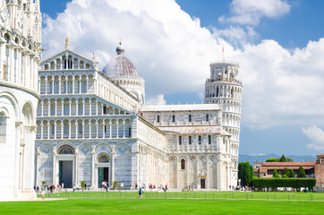 Fototapeta na wymiar Pisa Baptistery Battistero, Pisa Cathedral Duomo Cattedrale and Leaning Tower Torre on Piazza del Miracoli square green grass lawn, blue sky with white clouds background in sunny day, Tuscany, Italy
