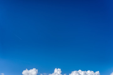 Fluffy white clouds against a bright, colorful blue sky