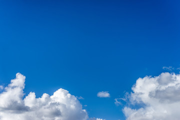 Fluffy white clouds against a bright, colorful blue sky