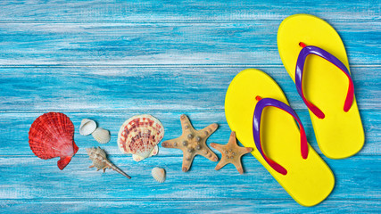 Bright yellow flip flops with seashells and starfish as concept of vacation time