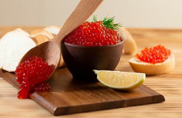 red caviar in a ceramic dish on a wooden background in a rustic style with space for text