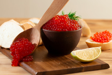 red caviar in a ceramic dish on a wooden background in a rustic style with space for text