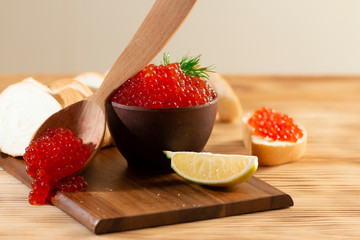 red caviar in a ceramic dish on a wooden background in a rustic style with space for text