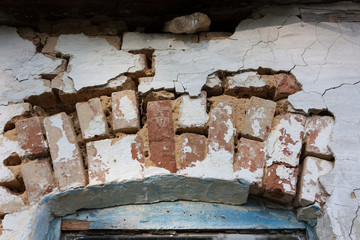 An old arch over a red brick window with partially preserved plaster.