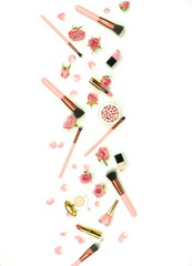 Makeup cosmetic accessories products  brushes, lipstick, pink flowers roses on white background. Flat lay. Top view. Copy space