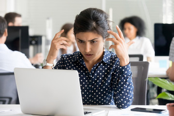 Upset female office worker reading unpleasant message