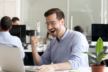 Excited man worker reading great offer sitting in office