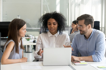 Three businesspeople working sharing information sitting at desk in office