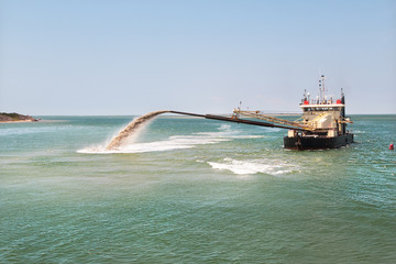 Dredge boat removing sand and silt from the bottom. Dredger ship works.Pumping sand.