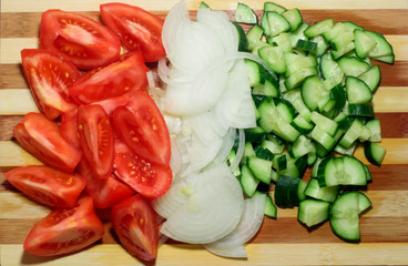 Sliced tomatoes, onions and cucumbers, put together to form alternating colors - red, white, green. Top view.