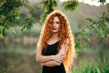 portrait af a beautiful redhead woman outdoors. stylish romantic young girl on a walk in the park....