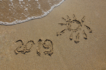 Summer vacation concept. Summer 2019 written on wet sand at the beach