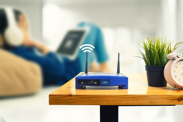 closeup of a wireless router and a man using smartphone on living room at home ofiice - obrazy, fototapety, plakaty
