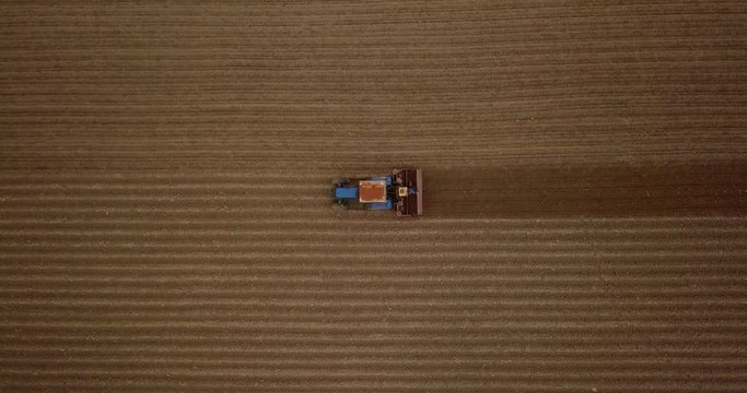 Farmer in tractor preparing land with seedbed cultivator. Agriculture. Tractor plowing field and preparing land for people who plant strawberry. Agronomy farming and husbandry concept. Aerial video.