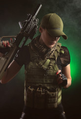 the girl in military special clothes posing with a gun in his hands on a dark background in the haze