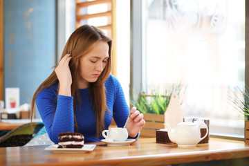 Young girl in cafe sits and drinks tea