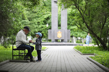 Grandpa is walking with her grandson in a spring park. Grandson and grandfather on a walk. Grandpa...