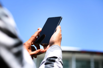 A man using smartphone in front of the office building.