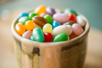 Jelly candy beans on a bowl. Close up view of candy beans with selective focus on wooden background.  