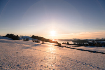 Sunset scenery in Winter: Lake, snowy fields and sundown. Wallersee, Austria