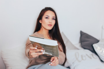 The beautiful long hair asian girl young woman sitting in bed with book, cozy home time