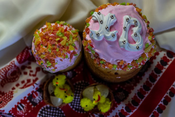 Several Kulich, a traditional Russian Easter bread with meringue and colorful sprinkles eggs on towel in the basket with chickens