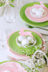 Happy easter. Decor and table setting of the Easter table is a vase with pink tulips and dishes of pink and green color.