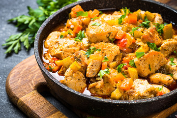 Chicken stew with vegetables black stone table, top view.