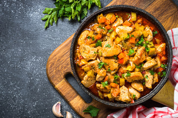 Chicken stew with vegetables black stone table, top view.