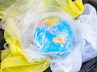 A terrestrial globe or planet Earth between garbage and plastic bags. Concept of ecology