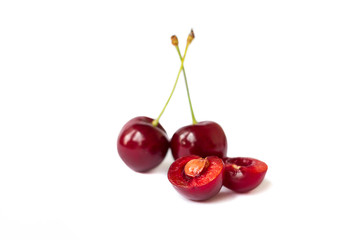 Two juicy cherries and one halved isolated on white