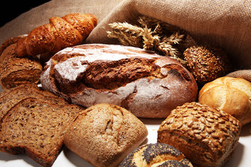 Different kinds of bread and bread rolls on board from above.