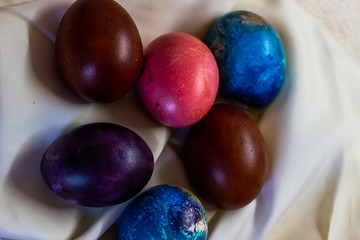 Fototapeta na wymiar Multicolored Easter eggs, painted with natural dyes on a white tablecloth. Painted traditional eggs for Easter holiday