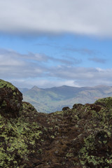 Dark rocks and mountain peak in distance with dramatic sky during sunny day